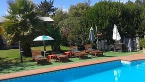Una piscina con sillones de playa y sombrillas.