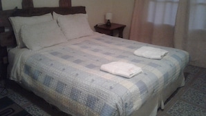 Una cama bien hecha con una colcha a cuadros, dos almohadas y dos toallas dobladas al pie de la cama.