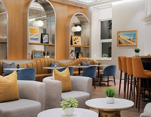 Ein stilvoller Lounge-Bereich mit Ledersitzmöbeln, runden Tischen und dekorativen Kissen.