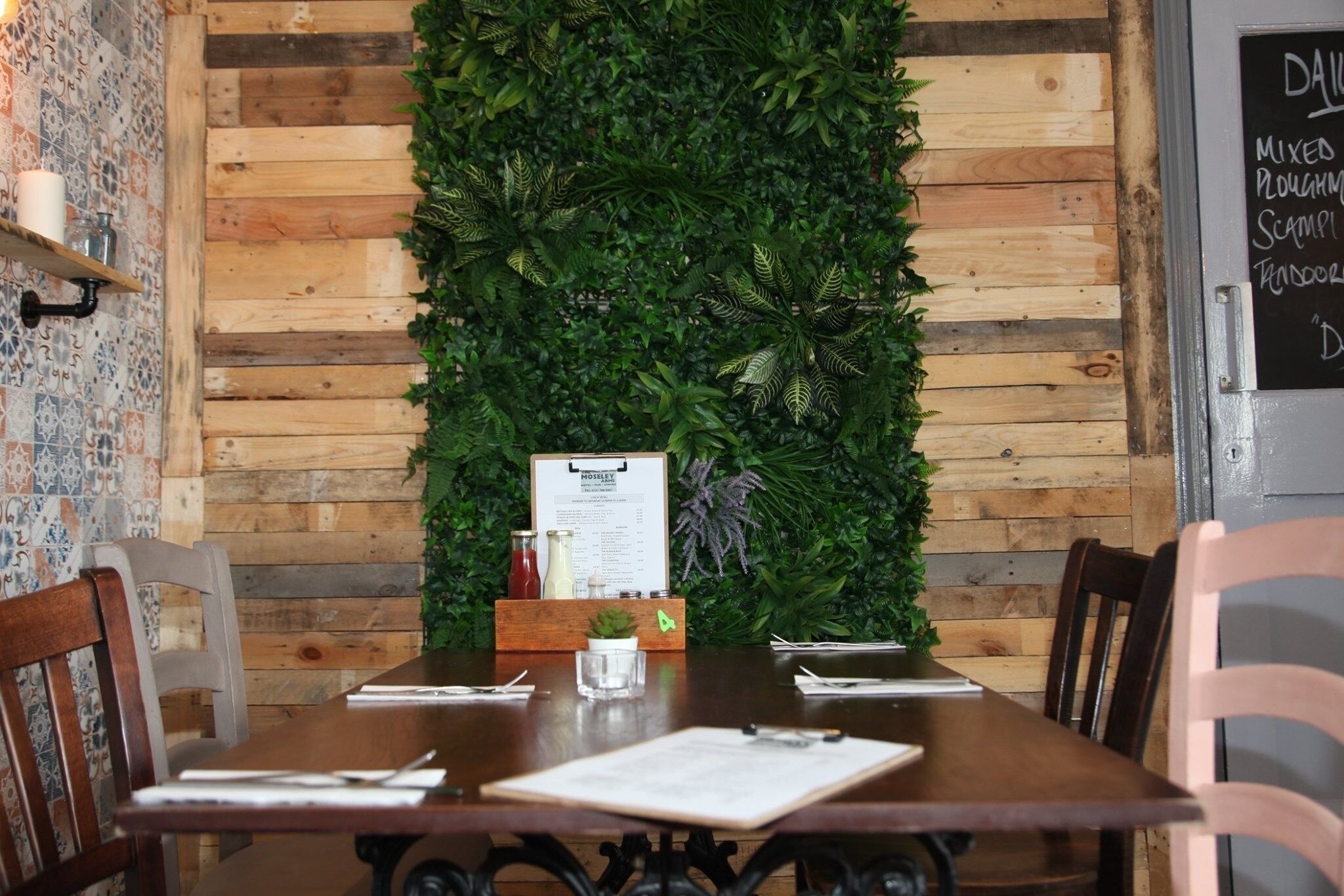 A wooden dining table with a menu stand in the center, surrounded by chairs.