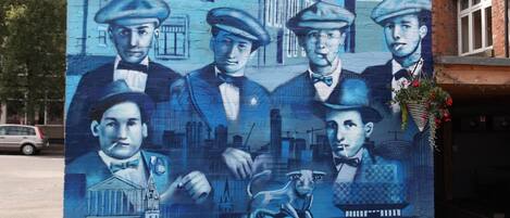 A mural with figures in suits and hats, a dog, and a building.