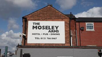Un edificio con un cartel que anuncia el Hotel, Pub y Restaurante The Moseley Arms.