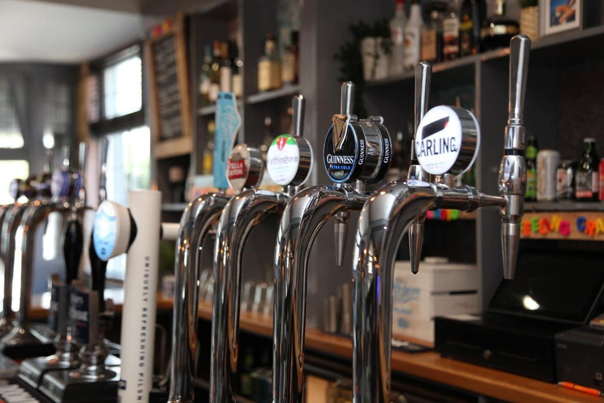 Una hilera de grifos de cerveza con etiquetas que incluyen Guinness, Carling y otras.