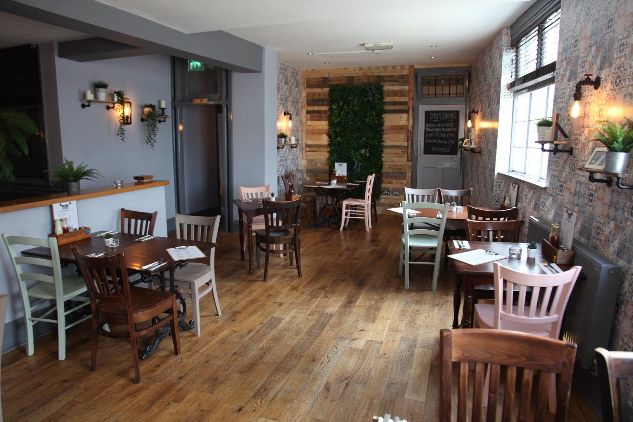 Interior de restaurante com soalho de madeira, várias mesas de jantar e cadeiras.