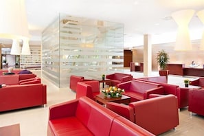 A modern lobby with red seating, a glass wall, and a reception desk. - Hotel Interferie Medical Spa (Swinoujscie)