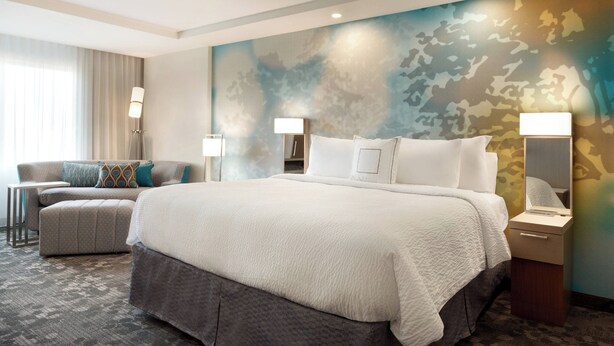 Une chambre d’hôtel avec un grand lit, un canapé, une petite table et une lampe.