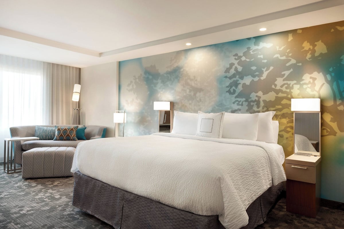 Ein Hotelzimmer mit einem großen Bett, einem Schlafsofa, einem kleinen Tisch und einer Lampe.