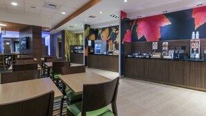 A restaurant with wooden tables and chairs, a counter with a coffee machine, and a colorful mural on the wall. - Fairfield Inn & Suites Boston Marlborough/Apex Center (Marlborough)