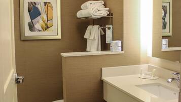 A bathroom with a toilet, a sink, and a mirror. There are towels and toilet paper on the wall.