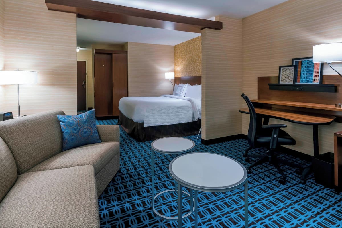 A hotel room with a bed, a sofa, a desk, and two small tables.