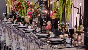 Une longue table à manger, agrémentée de nombreuses bougies, de vases et de compositions florales.