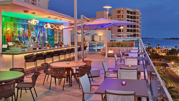 Un bar situé sur le toit, avec une terrasse, une piscine et une vue sur la mer.