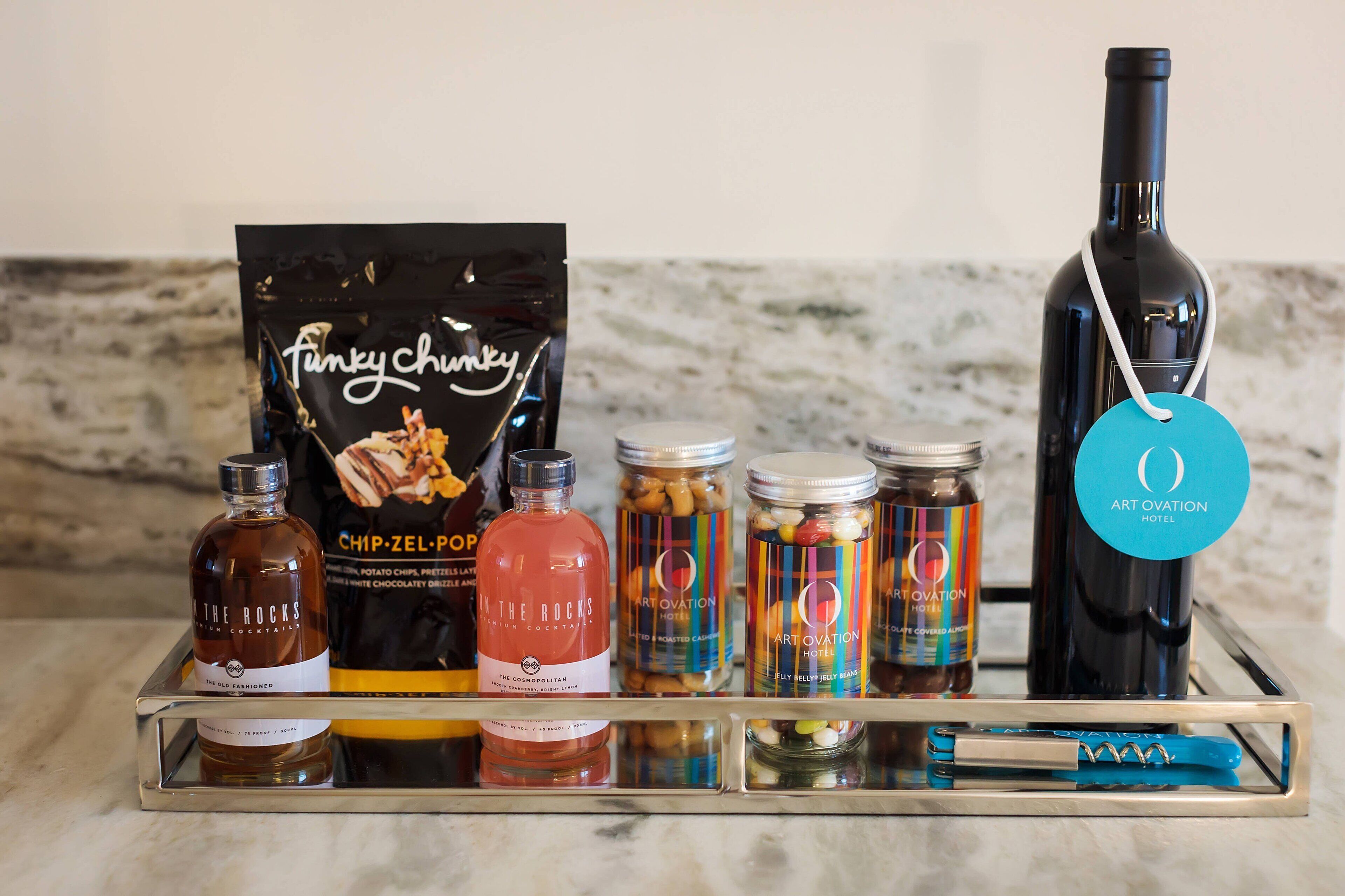 A tray with various food items and a bottle of wine, likely for a hotel or restaurant setting.