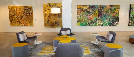 A lobby with modern seating, abstract art on the walls, and a central light fixture.