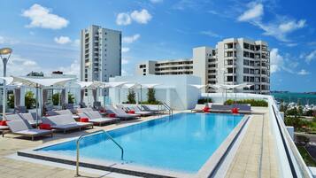 Una piscina al aire libre, camas de piscina con cargo, sombrillas