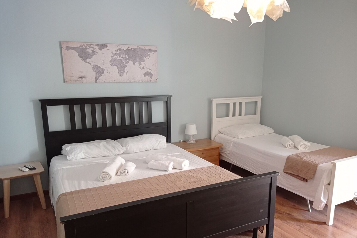 Quarto de hotel com duas camas, um mapa-múndi na parede e piso de madeira.
