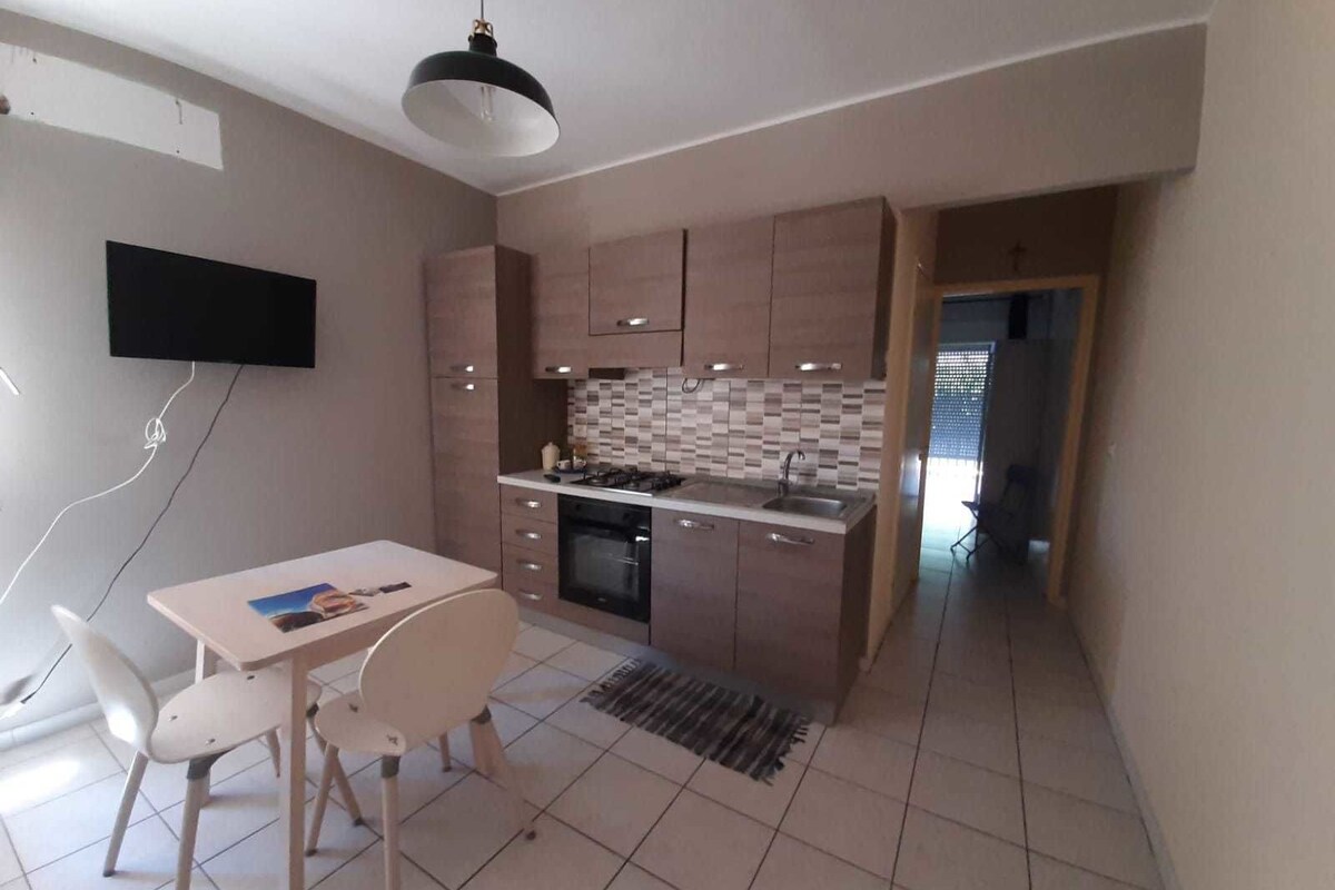Uma cozinha compacta com área de refeições, apresentando backsplash de azulejos, forno embutido e uma pequena mesa de jantar com cadeiras.