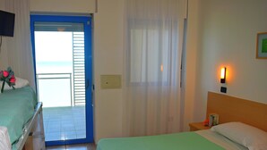 A hotel room with a bed, a nightstand, a lamp, and a view of the outside. - Hotel Atlantic (Senigallia)