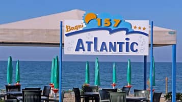 Un ristorante sulla spiaggia chiamato 'Bagni 157 Atlantic' con posti a sedere all'aperto e ombrelloni.