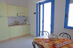 Una cocina con armarios amarillos, una encimera blanca y una mesa de comedor con mantel floral.
