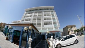 A modern building with a curved facade, large windows, and a covered entrance area. - Hotel Atlantic (Senigallia)