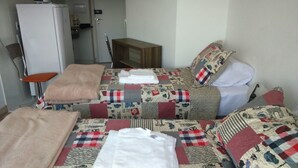 Ein Hotelzimmer mit zwei Betten, einem kleinen Tisch, einem Stuhl und einem Kühlschrank.