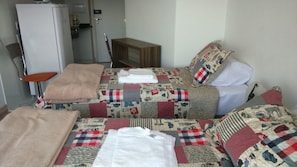 Habitación de hotel con dos camas, una mesita, una silla y un refrigerador.