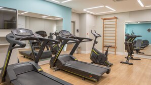 Ein Fitnessraum mit Laufbändern, Fahrrädern und einer Holzlade.