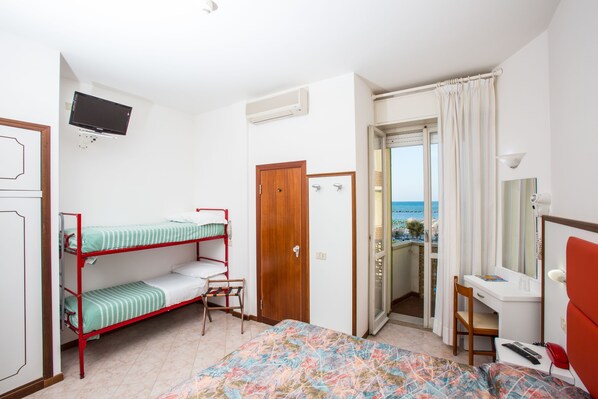 Una habitación con literas, un escritorio, una silla, un televisor y vista al mar.