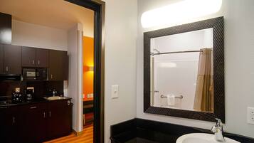 Une salle de bain d’hôtel avec un grand miroir, un lavabo et une douche.