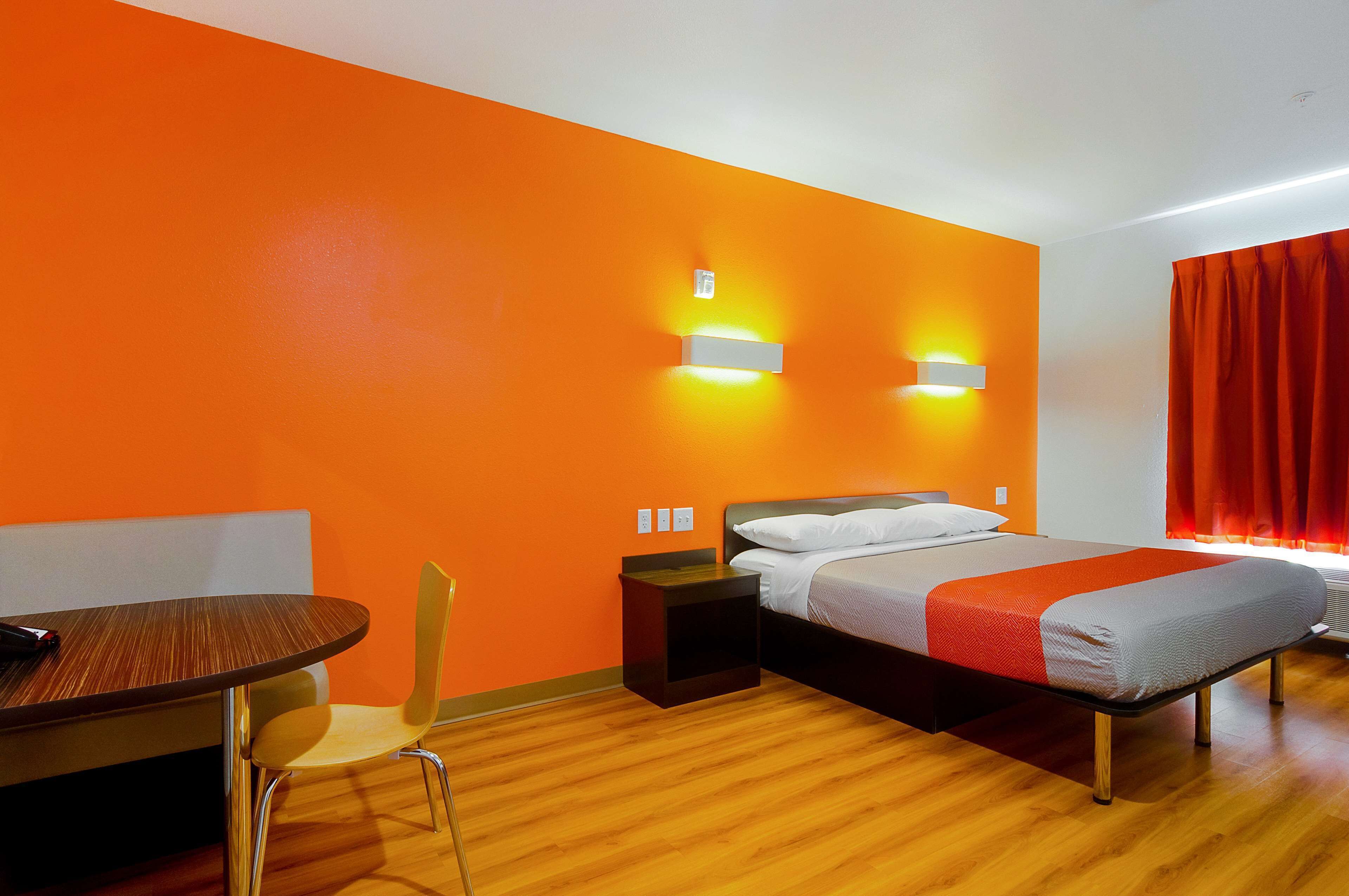 A hotel room with a bed, a bedside table, a chair, and a small table with a chair.