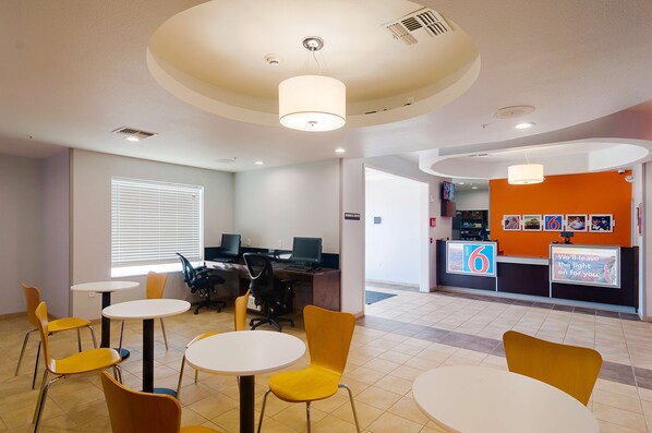 A reception area with a counter, chairs, tables, and computers. - Motel 6 Midland, TX (Midland)