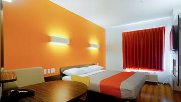 A hotel room with a bed, a table, and a TV.