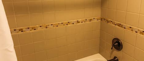 A bathroom with a bathtub, a showerhead, and tiled walls.