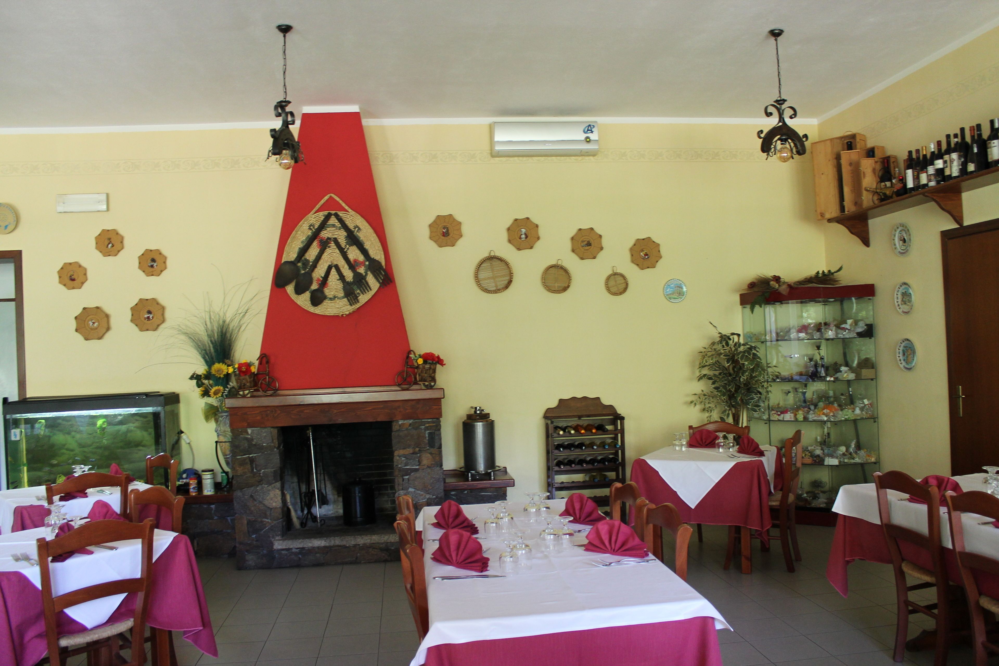 A dining area with tables set for a meal, a fireplace, and a wine rack.