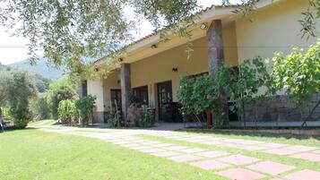 A building with a yellow facade, stone pillars, and a covered patio area.