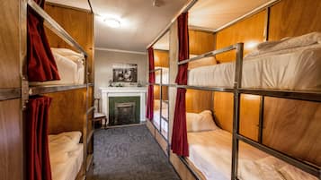 A train compartment with bunk beds, a fireplace, and a small seating area.