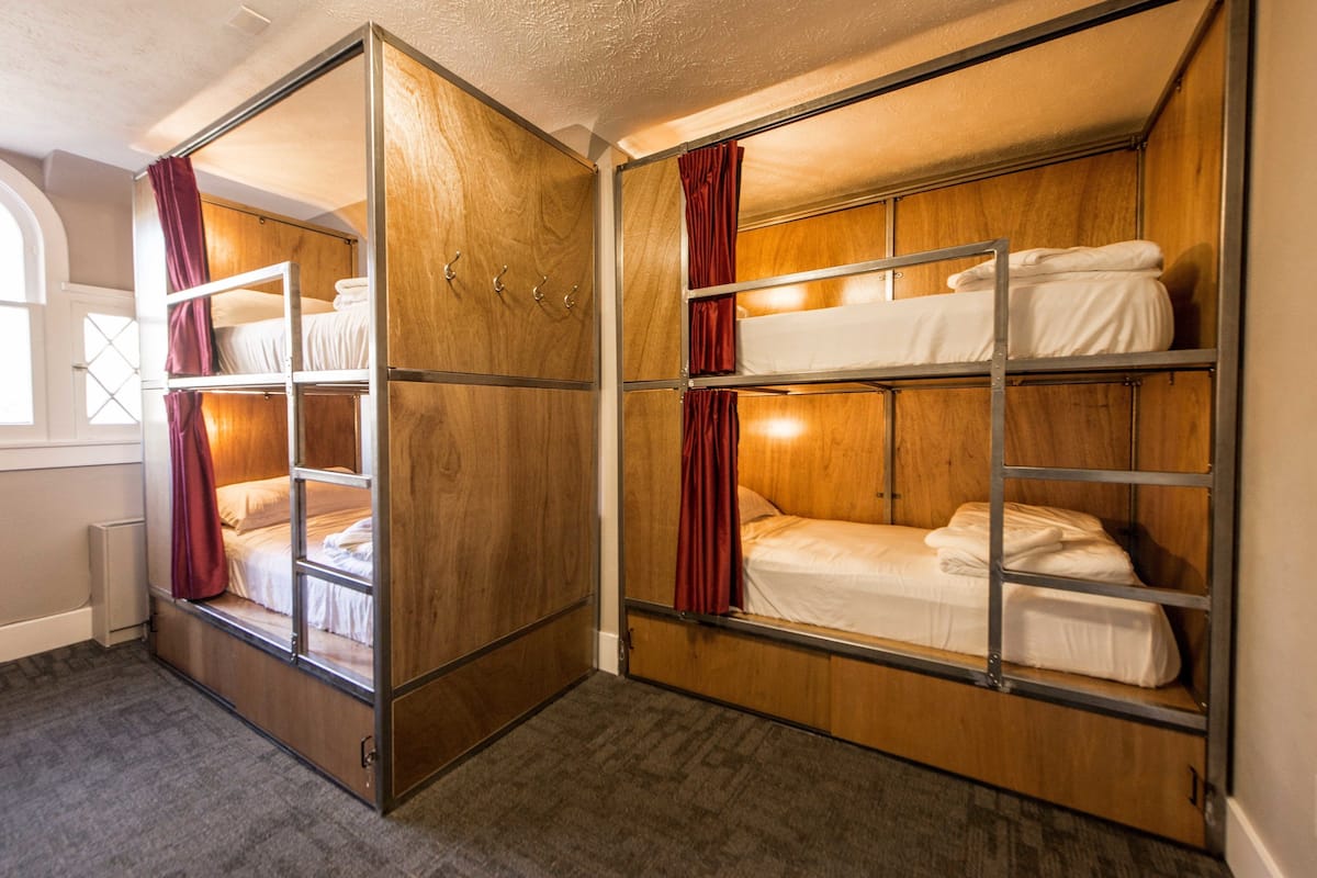 A room with bunk beds, wooden walls, and a window with a view.