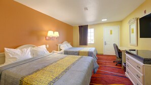 A hotel room with two beds, a desk, a chair, and a television.