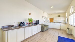 A spacious kitchen with a large island, white cabinetry, and a blue rug.