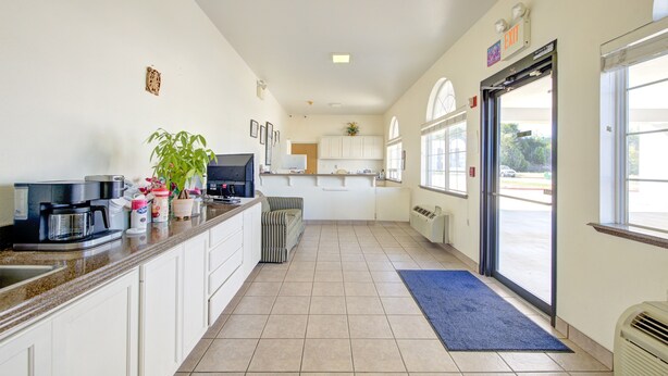 A kitchen with white cabinets, a coffee maker, a microwave, and a striped chair.