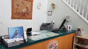 A reception desk with a computer, printer, and a framed picture of a bird. - Countryside Inn (Princeton)