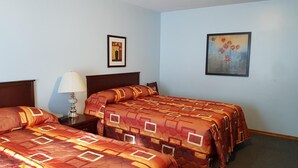 A hotel room with two beds, a nightstand with a lamp, and two framed artworks on the walls. - Countryside Inn (Princeton)