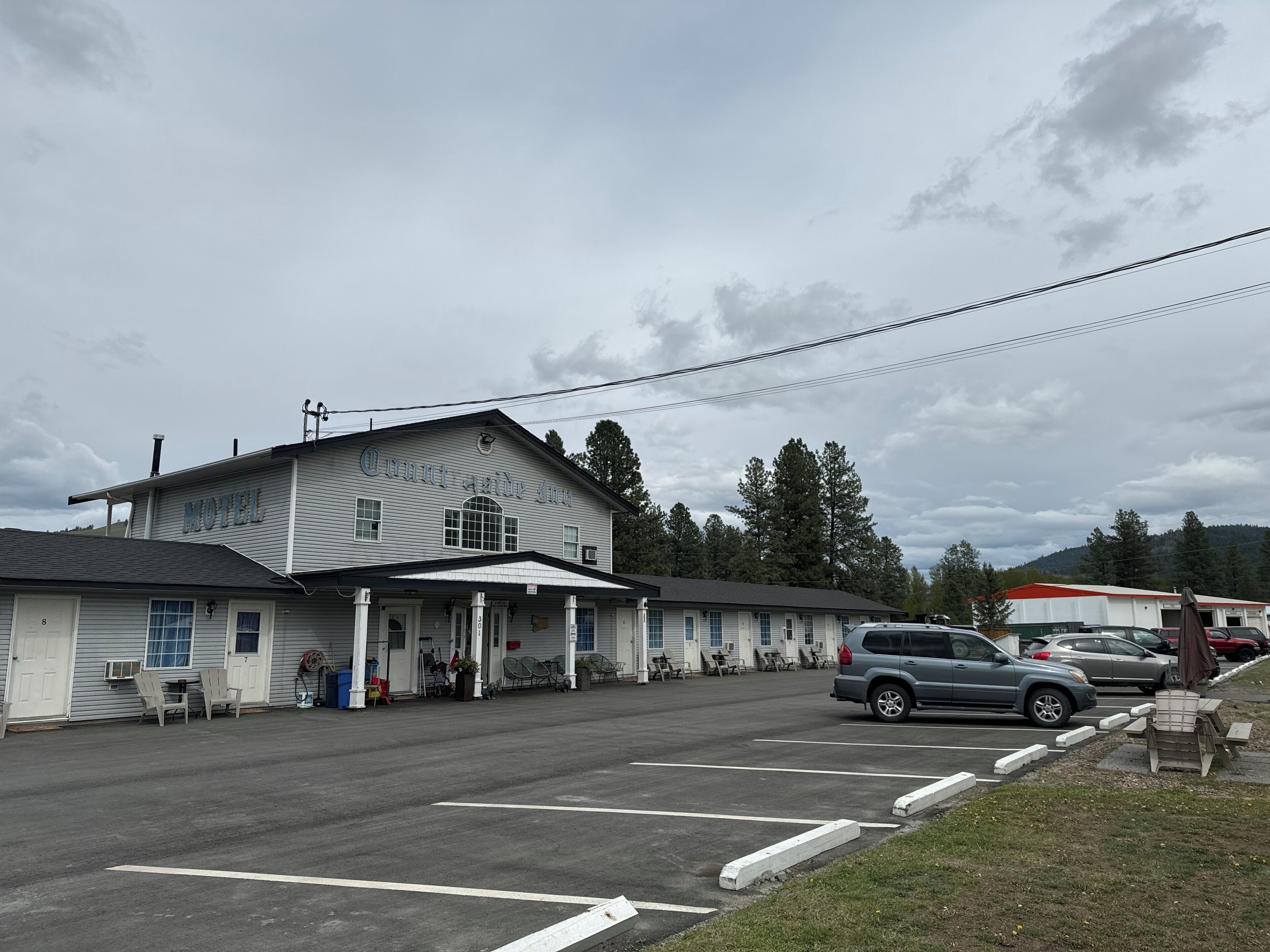 A motel with a covered entrance, outdoor seating, and a parking lot.