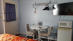 A small room with a bed, a table with two chairs, a television, and a microwave.