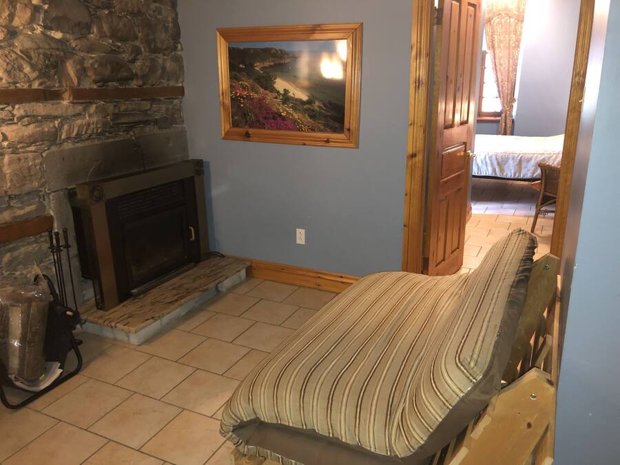A room with a stone fireplace, a bed with striped bedding, and a painting of a coastal landscape.