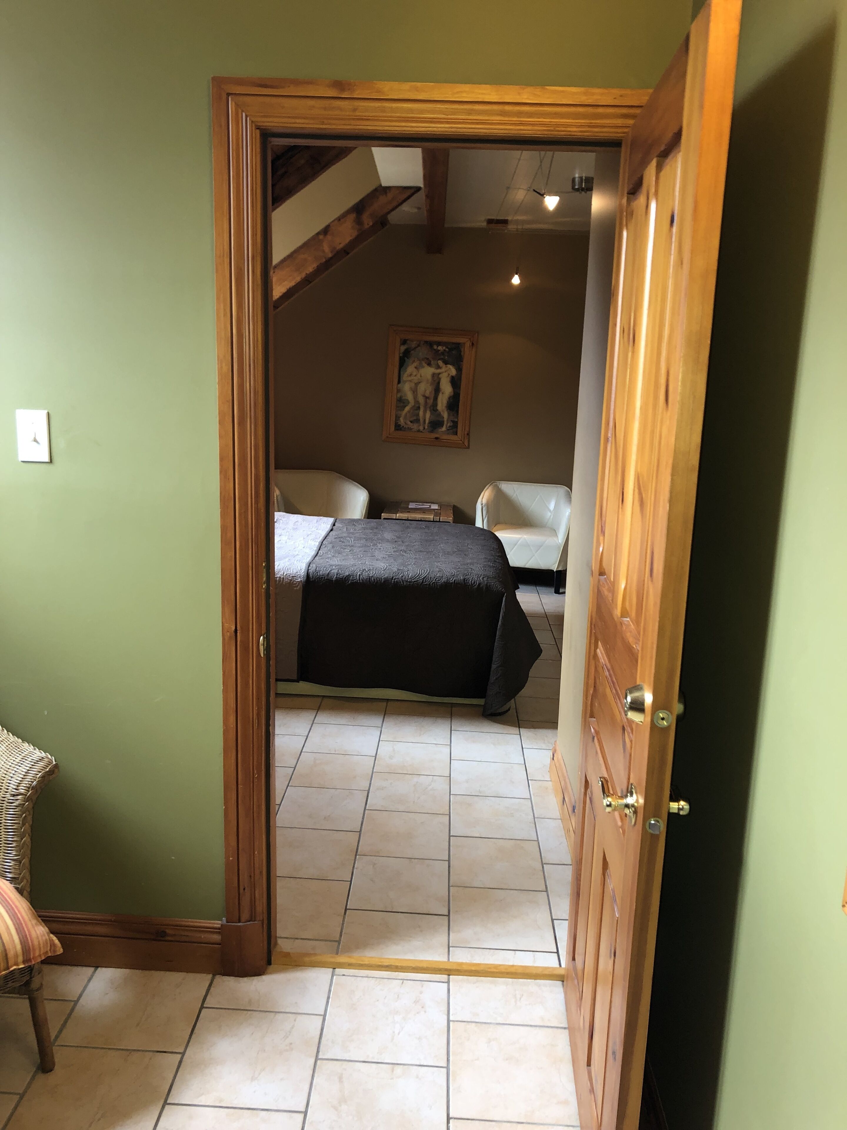 Een slaapkamer met een bed, een stoel en een schilderij aan de muur.