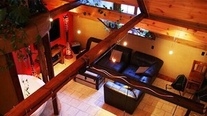Un interior acogedor y rústico con techo de madera, un sofá, una mesa de comedor y sillas.