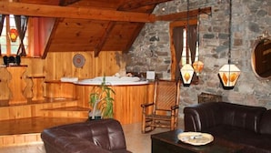 Una habitación acogedora con techo de madera, paredes de piedra, barra de madera, mobiliario de cuero y faroles colgantes.