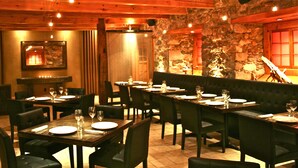 Un restaurante con varias mesas dispuestas para comer, paredes de piedra y una chimenea.